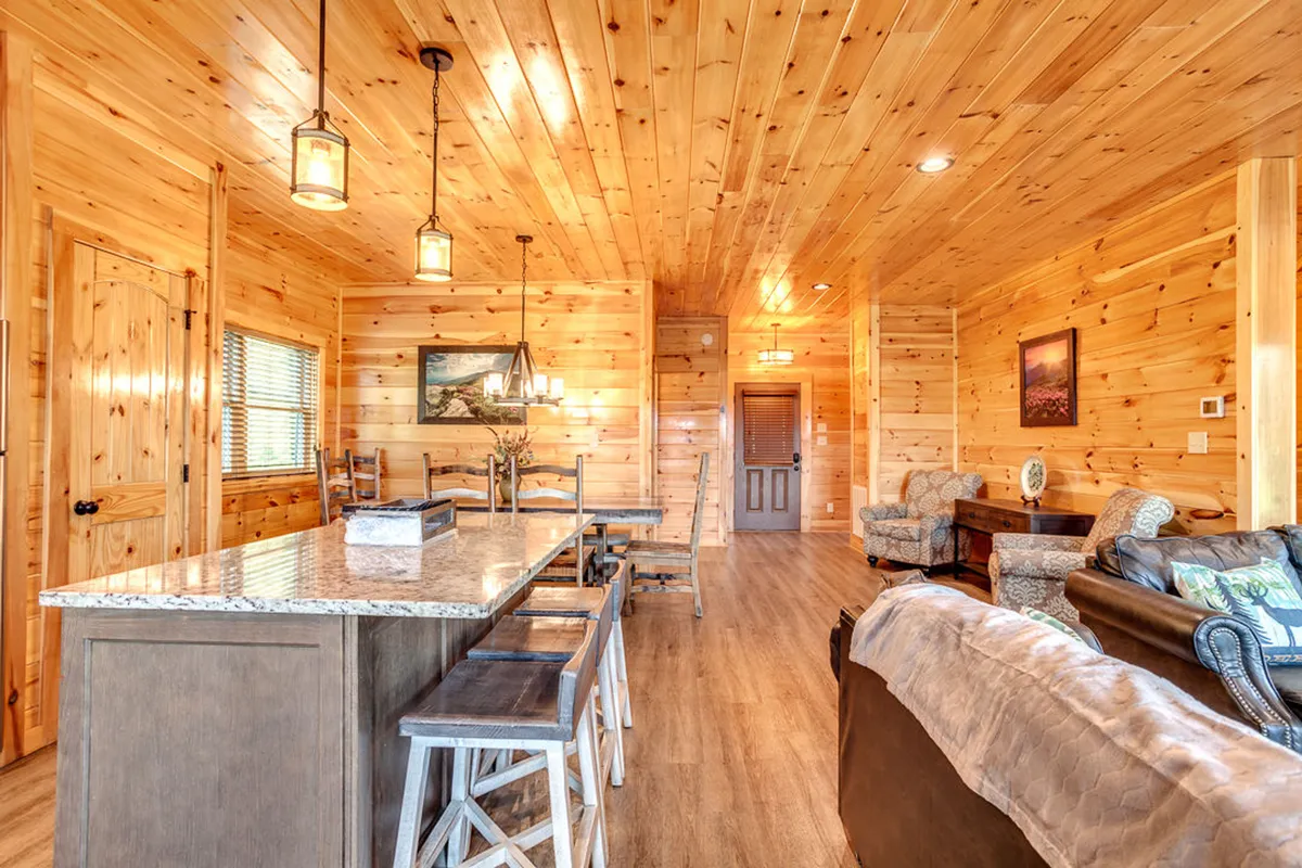 A cozy dining space anchored by a wooden dining table, granite countertop, comfortable seating, and hanging light fixtures. The space exudes a welcoming, festive atmosphere, perfect for sharing meals and conversation.