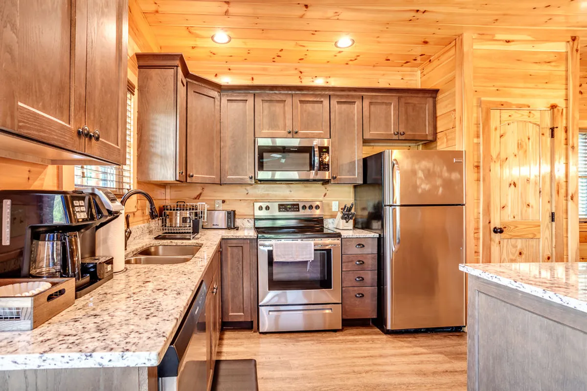 A modern kitchen with granite countertops, stainless steel appliances, warm wooden cabinetry, and ample space for meal preparation. The kitchen appears both functional and inviting, ideal for cooking together or entertaining guests.